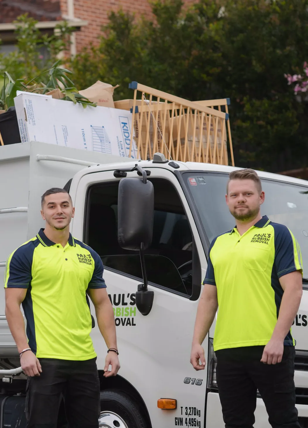 Two of the crew standing beside the loaded truck outside a Sydney home
